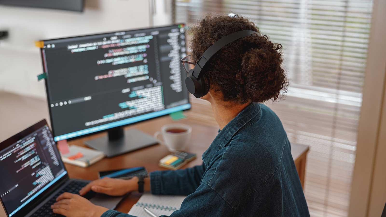 Person sitting at desk with monitors working on coding representing 计算机科学 program at Clarkson