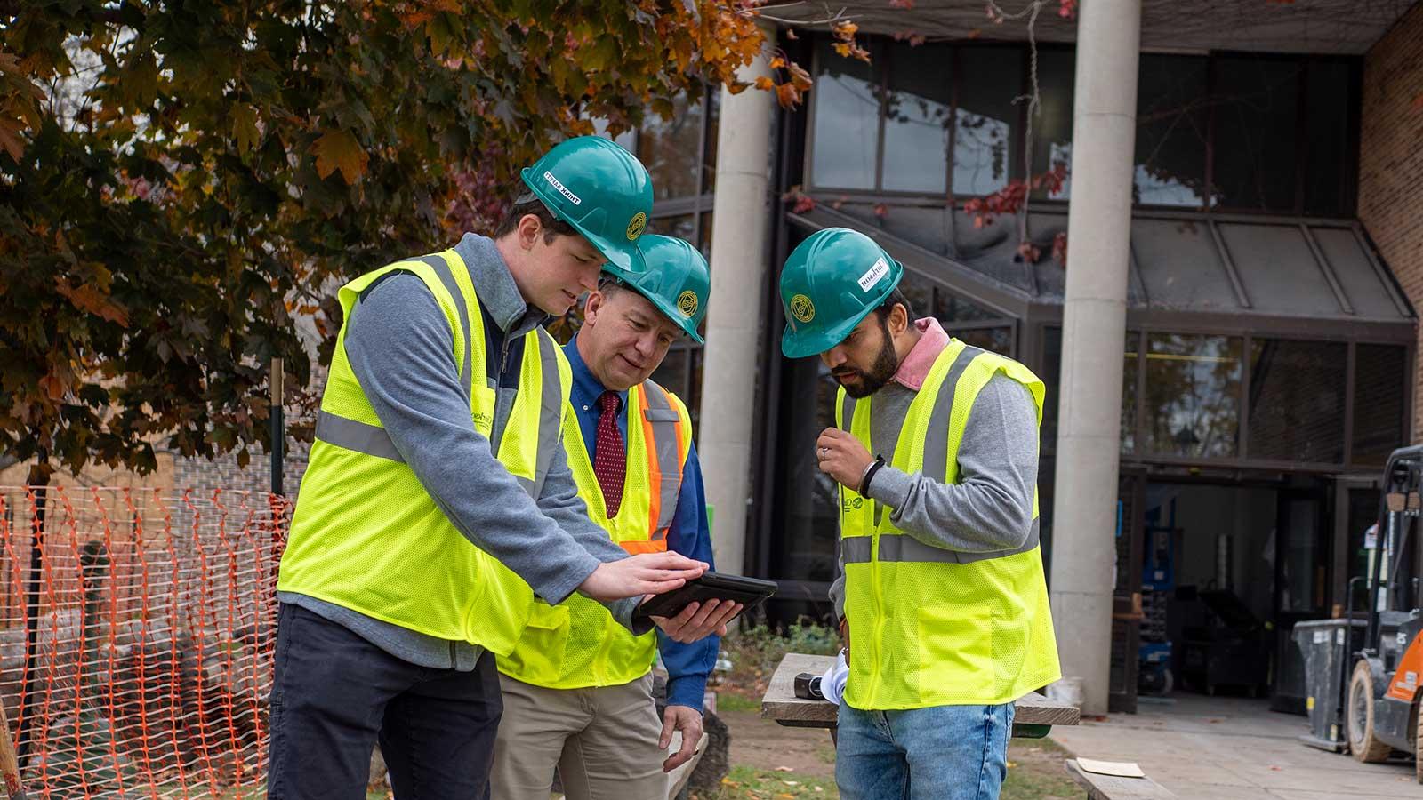 Construction Engineers looking at a tablet on a job site representing construction engineering management program at Clarkson university 